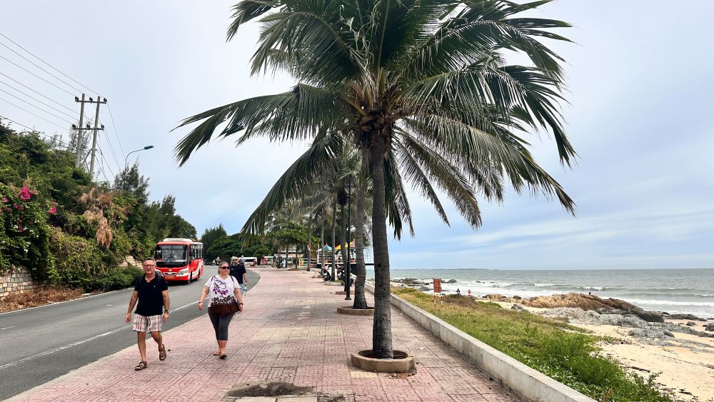Du khách nước ngoài đi dạo dọc bờ biển ở Phan Thiết.
