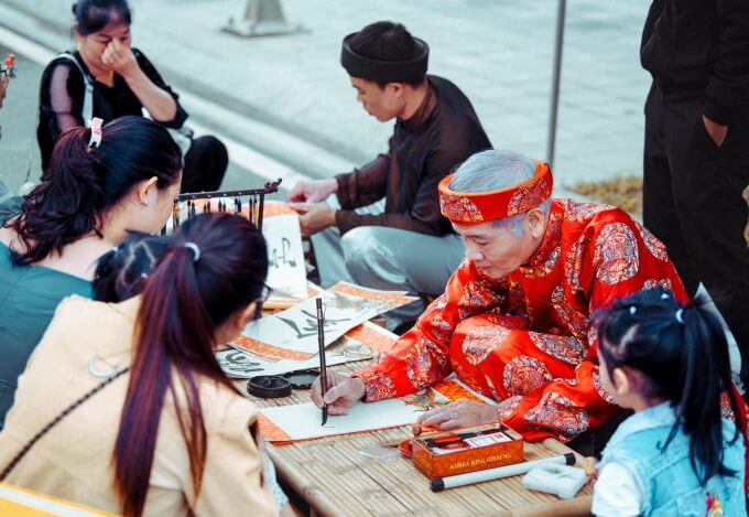 Du khách xem viết thư pháp tại hội chợ.