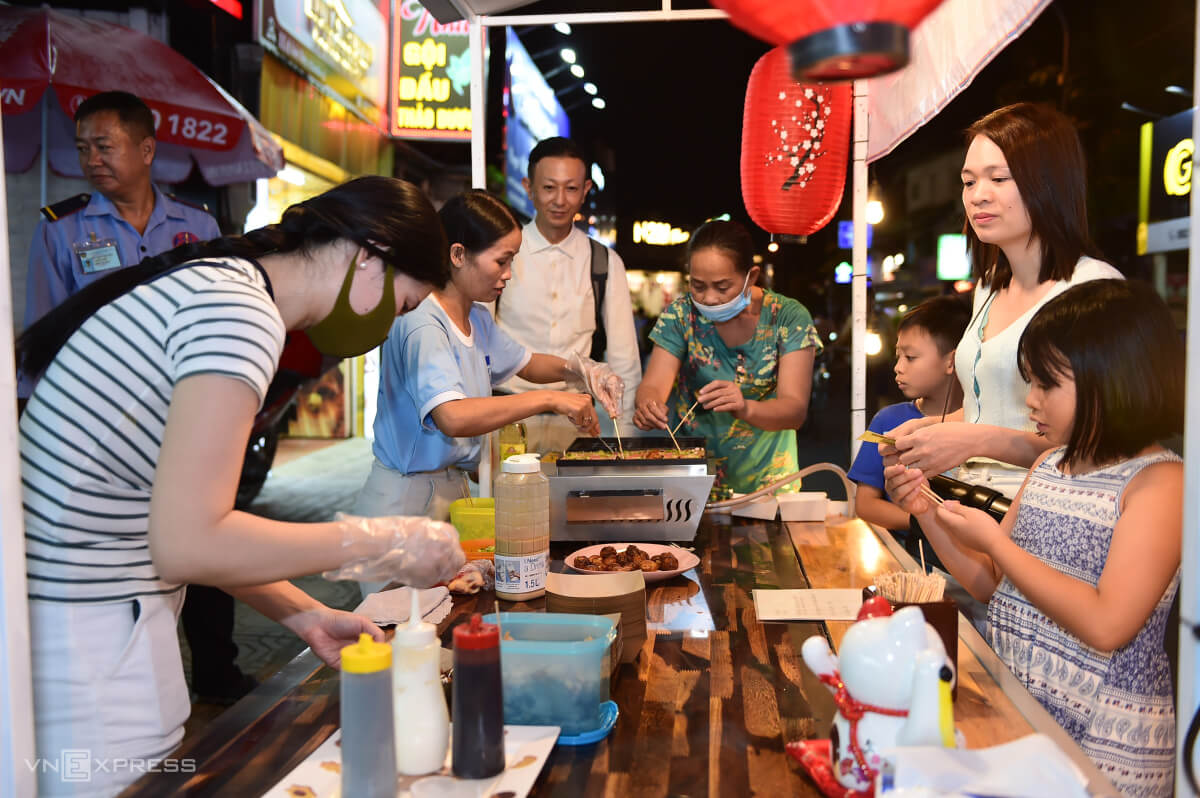 Vừa bày món bánh bạch tuộc ra bán, chị Nguyễn Thị Minh Thái (thứ hai, trái) không kịp ngơi tay.
