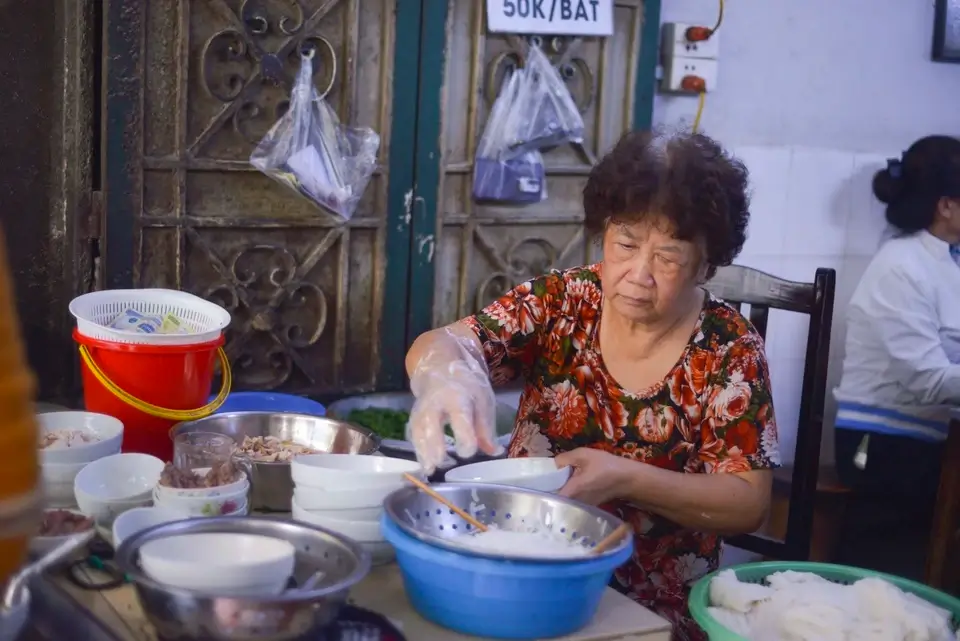 Bước vào quán, ấn tượng đầu tiên là hình ảnh bà chủ ngồi ở quầy chế biến ngoài cửa, tay thoăn thoắt làm phở.