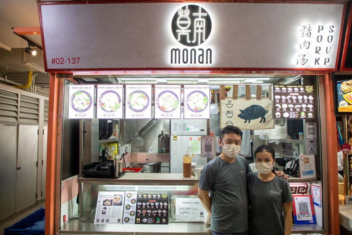 Hai vợ chồng chủ quán chụp ảnh trước nhà hàng của mình.